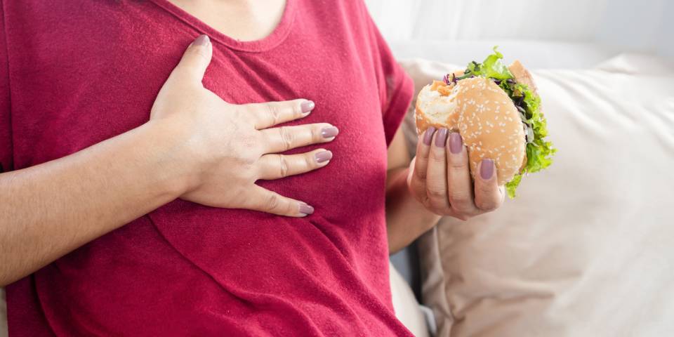 A person experiencing chest discomfort after eating junk food, showing the importance of understanding what to eat and avoid for acidity and gas problems.